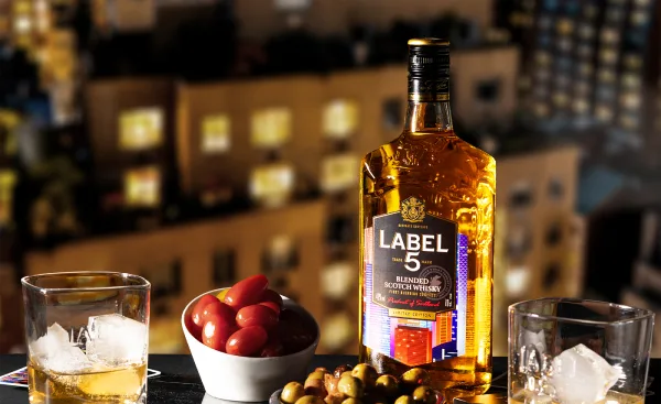 Bouteille blended scotch édition limité avec ville lumineuse en arrière plan. Apéro en premier plan